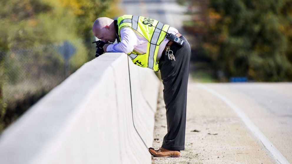 Genesee County Sheriff's Office investigator takes photos from an overpass on Oct. 20, 2017, in Vienna Township, Mich. where a rock was thrown from, smashing a car windshield and killing a 32-year-old man on Oct. 18. 