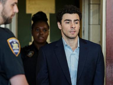Luigi Mangione in a dark suit sits at a defense table during an evidence suppression hearing in New York.