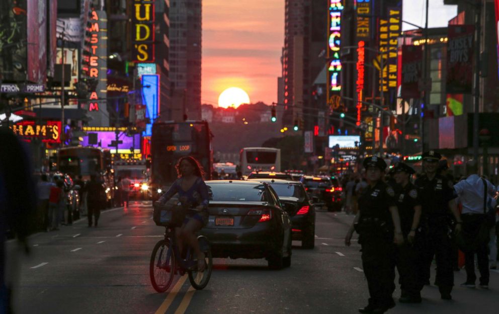 PHOTO: A woman rides a bike on 42nd Street in New York City during Manhattanhenge, July 12 2016.