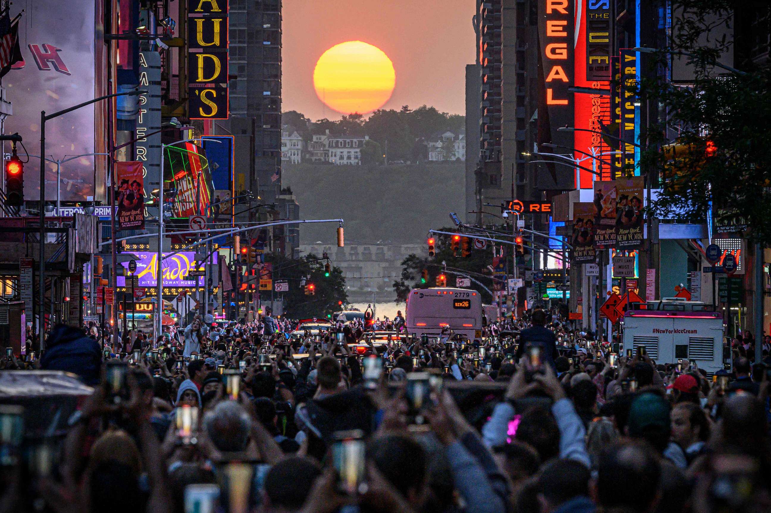 PHOTO: Crowds of viewers on 42nd street record the sun as it sets in alignment with Manhattan streets running east-west, also known as Manhattanhenge, in New York City on May 30, 2023.