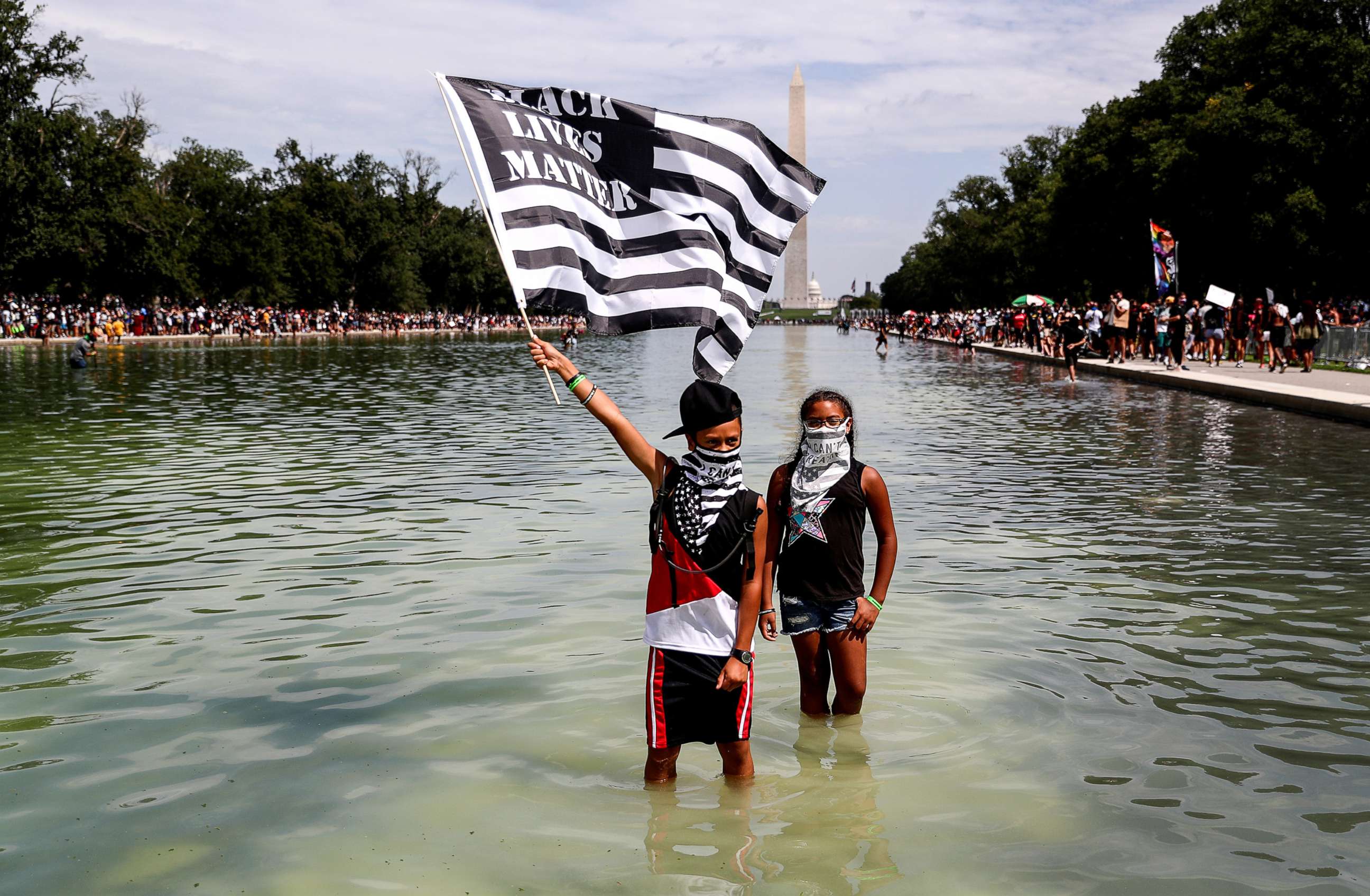 PHOTO: A demonstrator holds a Black Lives Matter flag as he wades into the waters of the Lincoln Memorial reflecting pool as protesters gather in Washington, D.C., Aug. 28, 2020. 