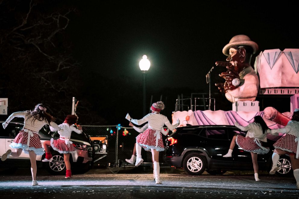 PHOTO: The Mande Milkshakers dance for vehicles driving by during the Mardi Gras Float in the Oaks event in City Park, Feb. 14, 2021, in New Orleans, Louisiana.