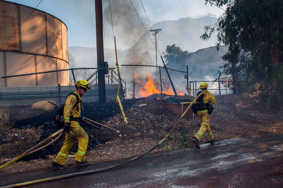 PHOTO: Firefighters run to battle flames from the Maria Fire next to a oil tank at South Mountain Road, in Santa Paula, Ventura County, in California on Nov. 01, 2019.