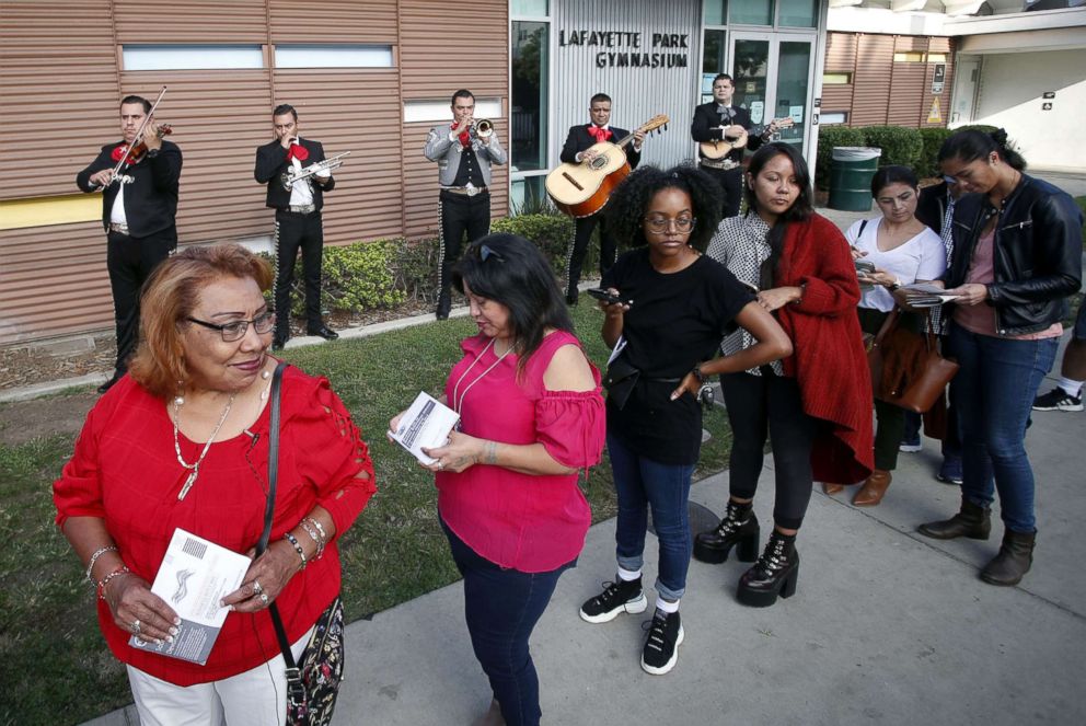 PHOTO: Latino voters Griselda Sanchez, left and Evelyn Franco, second from left, wait in line while being serenaded by mariachis at the Lafayette Park Gymnasium polling station in Los Angeles, Calif., Nov. 6, 2018.