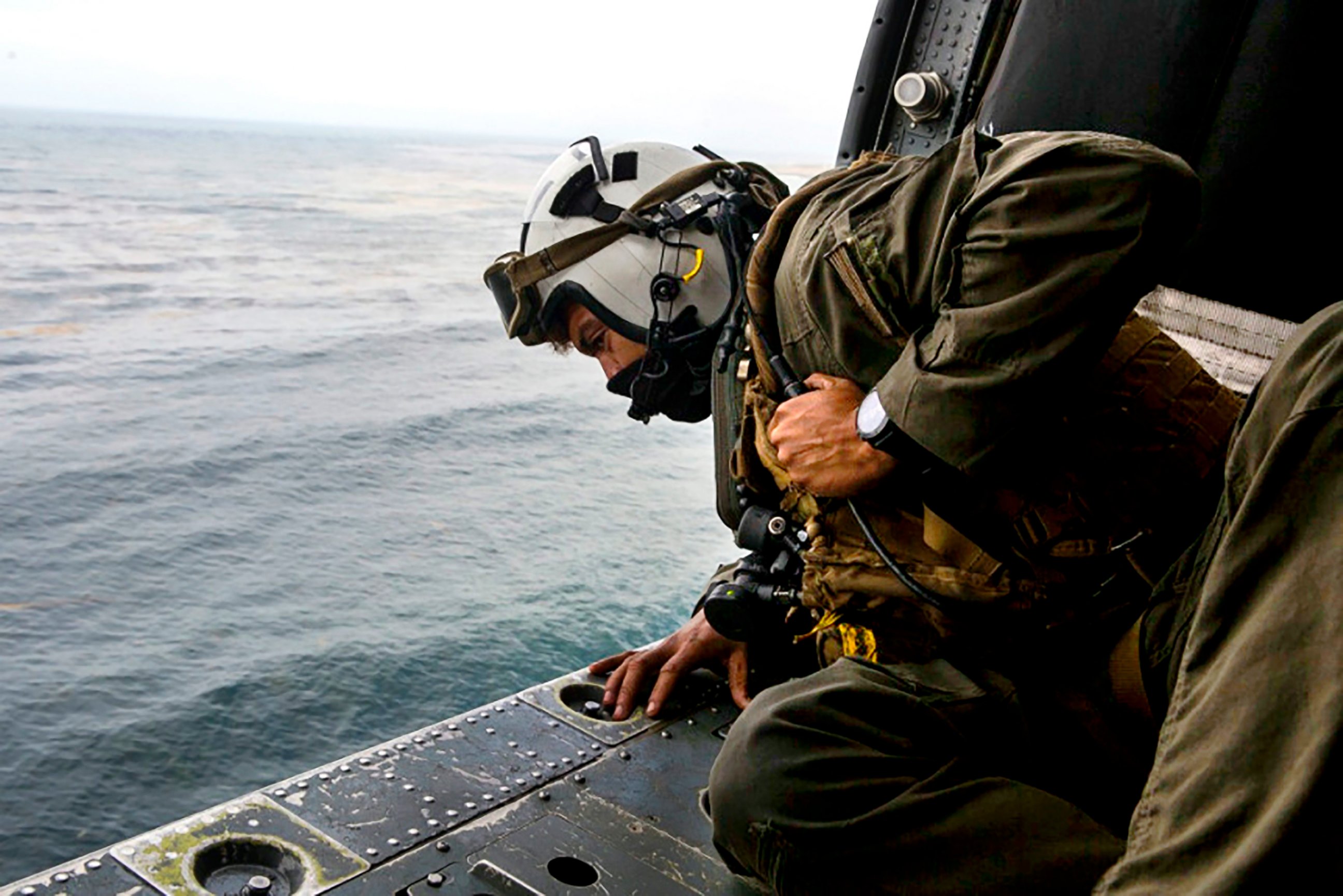 PHOTO: Naval Air Crewman 2nd Class Joseph Rivera, a search and rescue swimmer, looks out of a MH-60 Seahawk on Thursday, July 30, 2020, while searching for an assault amphibious vehicle that sank during a mishap off the coast of Southern California.