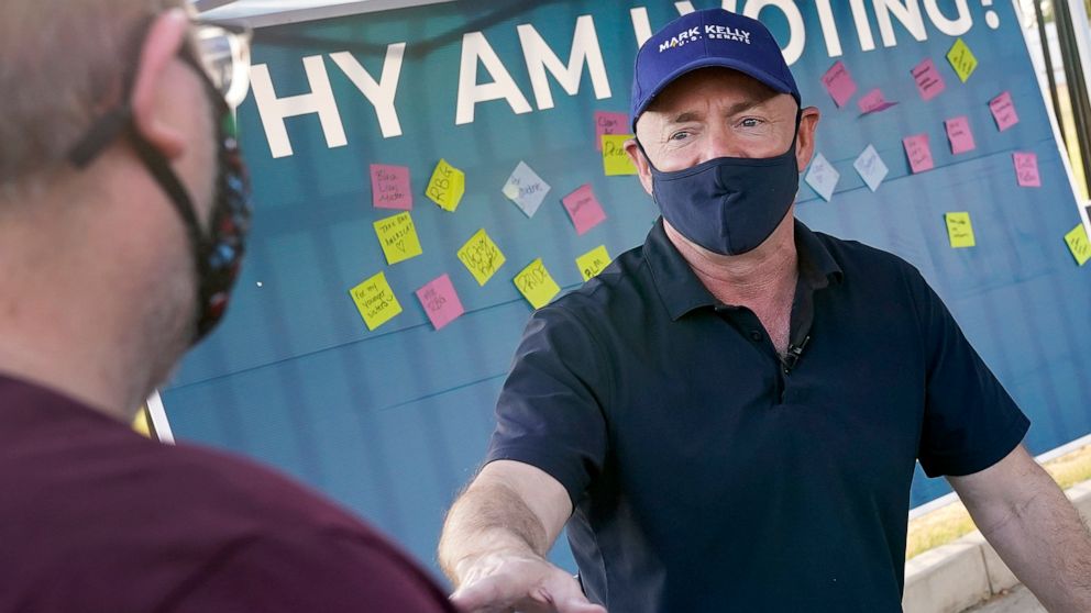 PHOTO: Mark Kelly, Democratic candidate for the Senate, greets voters at a polling station in Phoenix, Ariz., Nov. 3, 2020.
