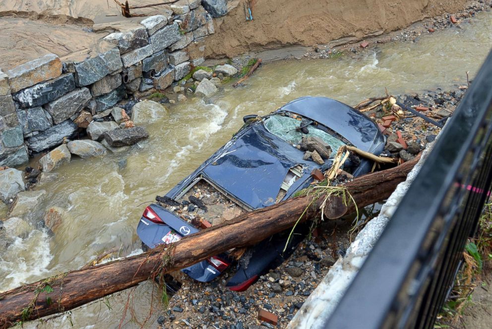 PHOTO: Water moves past a car swept into the riverbank and smashed by a fallen tree just off Main Street in flood-ravaged Ellicott City, Md., May 28, 2018.