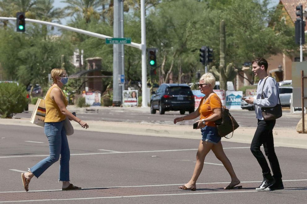 PHOTO: People cross the street between Kierland Commons and Scottsdale Quarter with and without face coverings, during the global outbreak of the coronavirus disease (COVID-19), in Scottsdale, Ariz., June 18, 2020.    