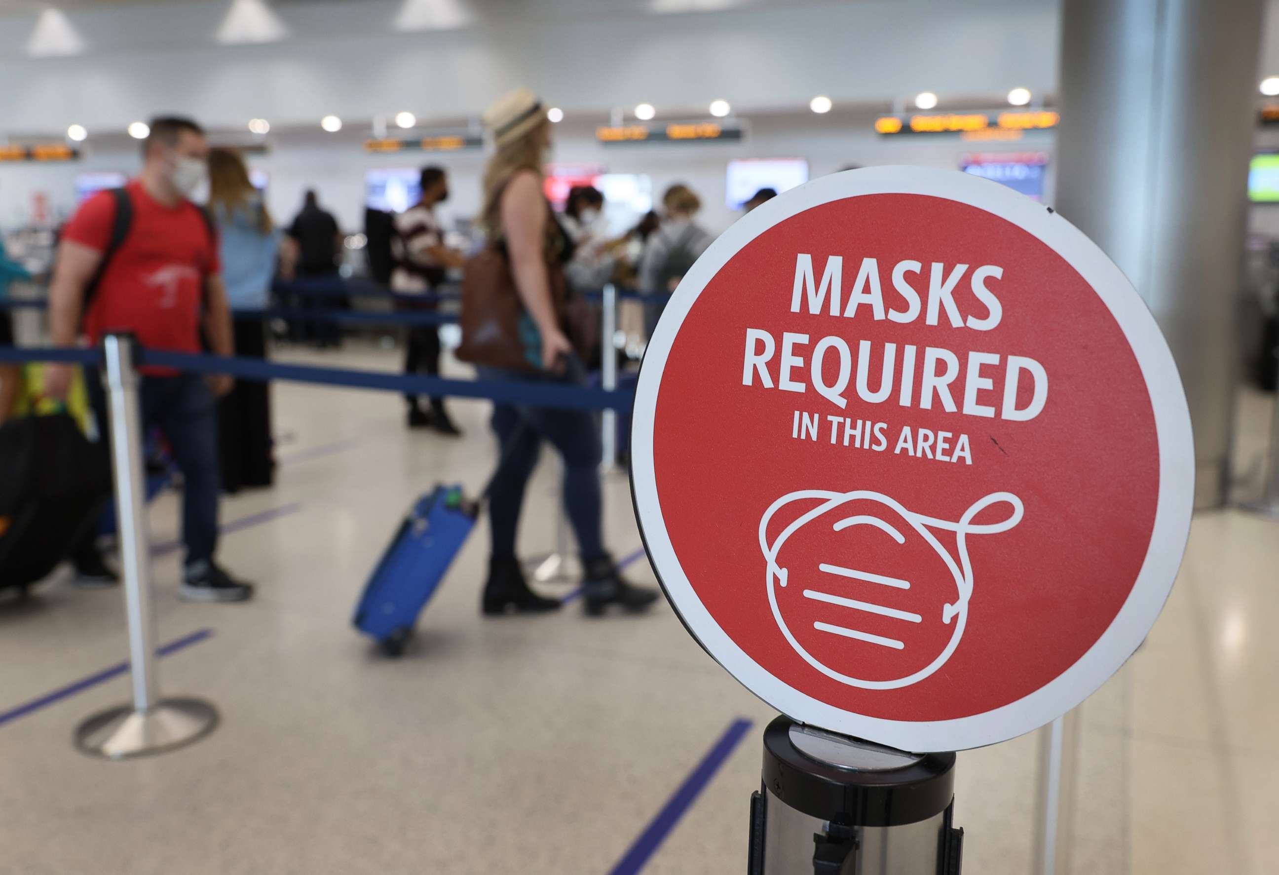 PHOTO: A sign reading, 'masks required in this area,' is seen as travelers prepare to check-in at the Miami International Airport, Feb. 1, 2021 in Miami, Fla.