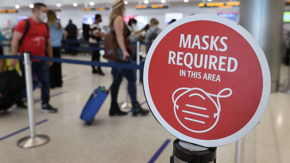 PHOTO: A sign reading, 'masks required in this area,' is seen as travelers prepare to check-in at the Miami International Airport, Feb. 1, 2021 in Miami, Fla.