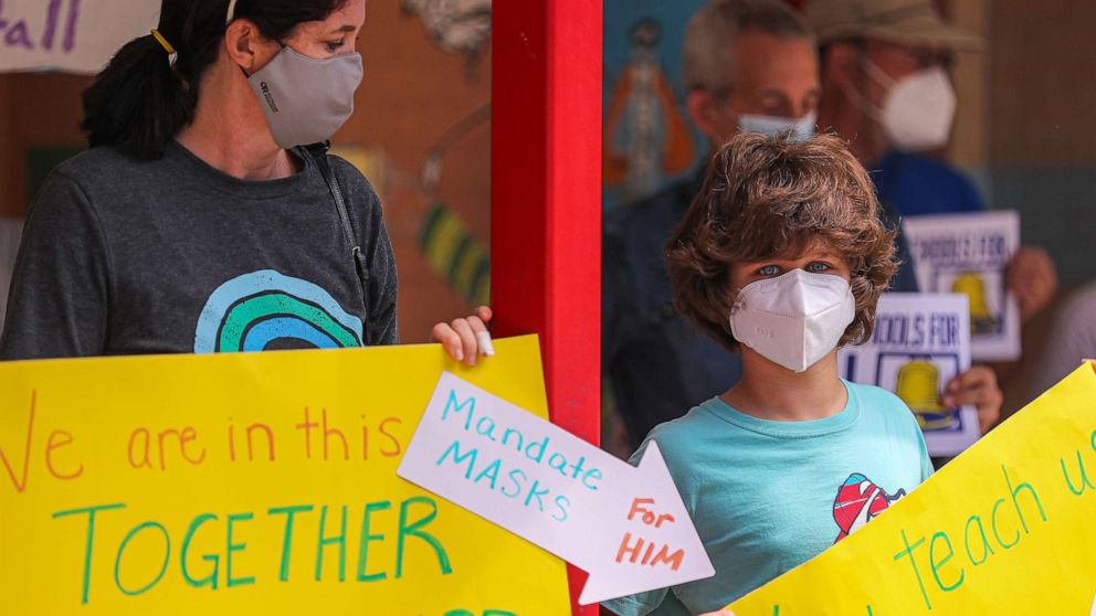 PHOTO: Milana Noueilaty stands with her son, Kaden, holding signs in support of mask mandates on Aug. 9, 2021.