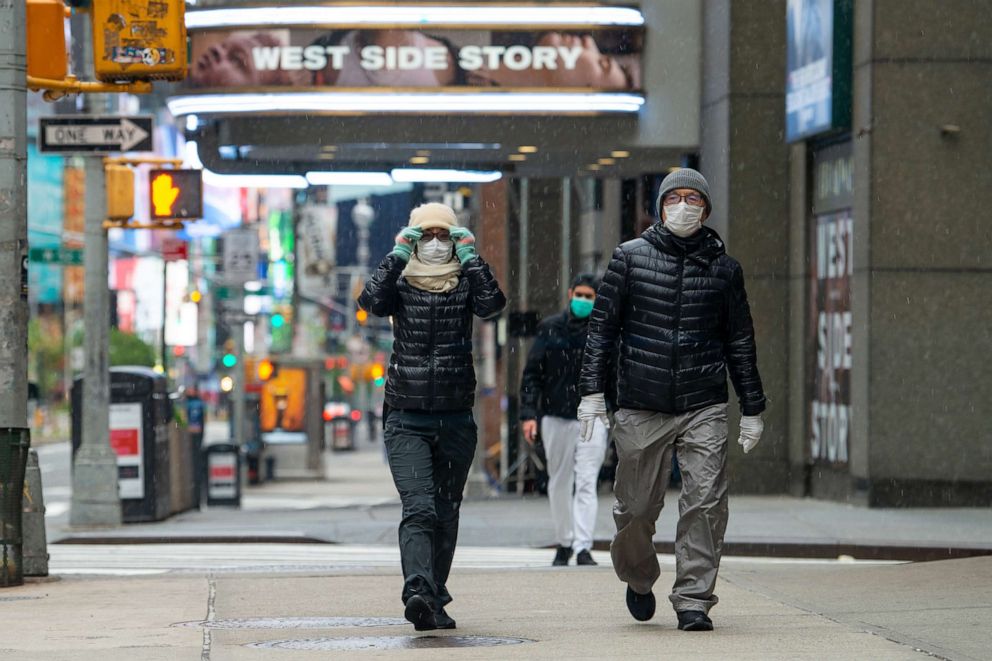 PHOTO: People wearing masks, gloves and winter coats walk in the snow amid the coronavirus pandemic on May 9, 2020 in New York City.