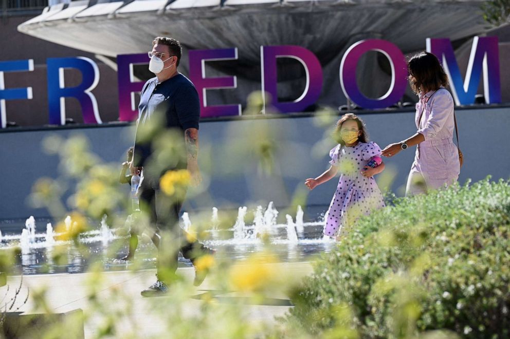 PHOTO: People wearing face masks walk past a sign reading "Freedom," in downtown Los Angeles, July 1, 2021.