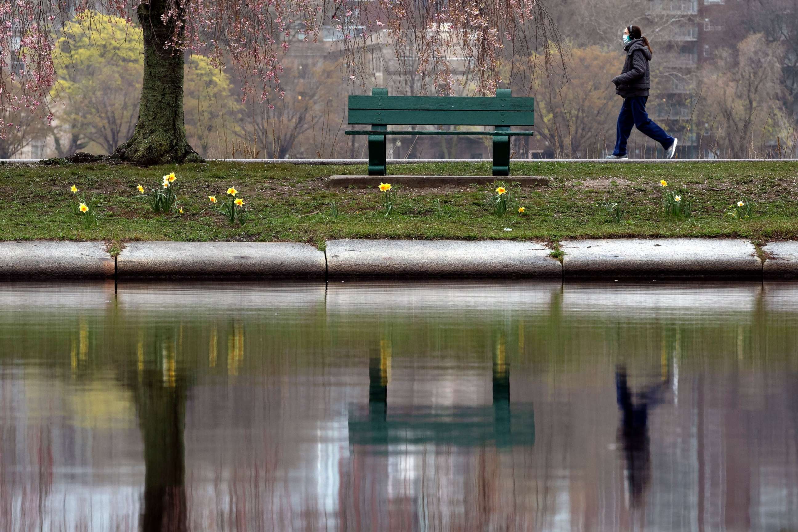 PHOTO: A woman wearing a protective mask walks along the Esplanade, May 1, 2020, in Boston. 