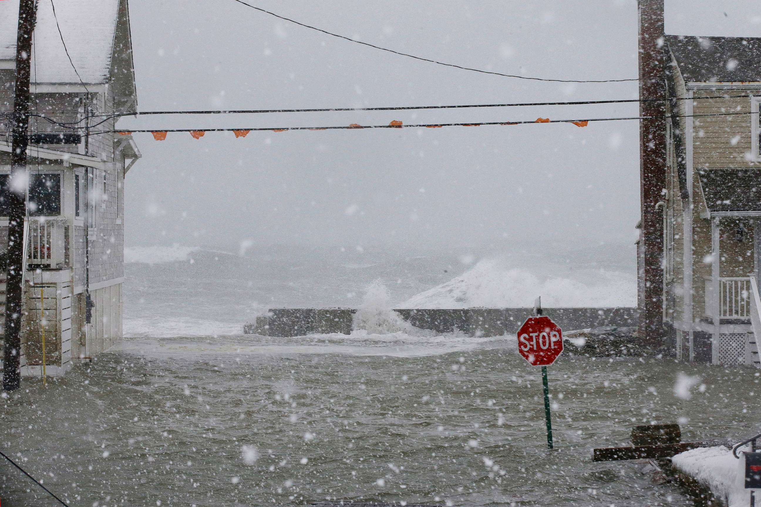 PHOTO: Water rushes over the seawall between two houses, Jan. 4, 2018, in Scituate, Mass. 