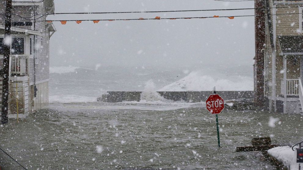 PHOTO: Water rushes over the seawall between two houses, Jan. 4, 2018, in Scituate, Mass.