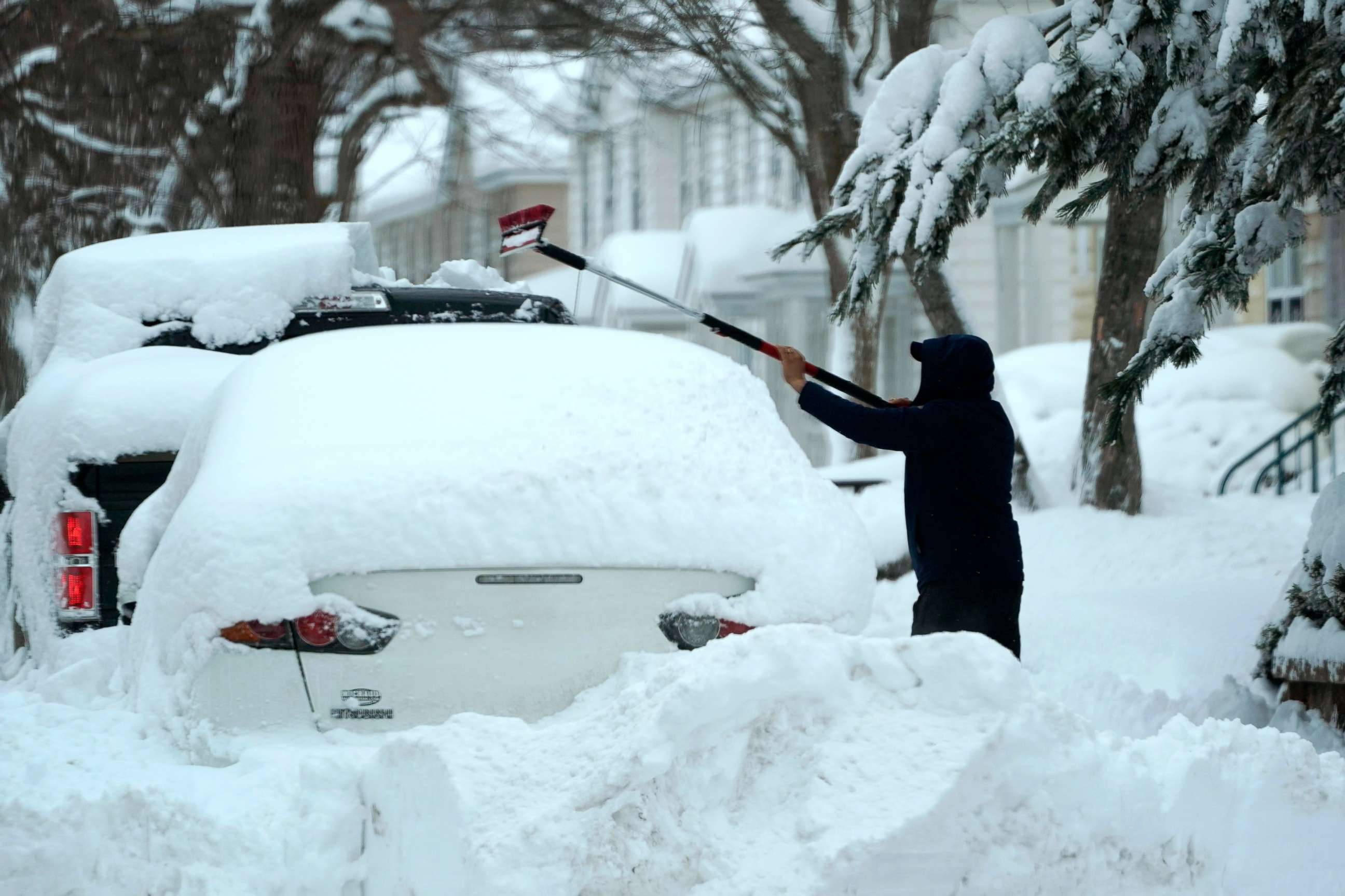 PHOTO: A man brushes snow off a car, Feb. 2, 2021, in Lawrence, Mass.