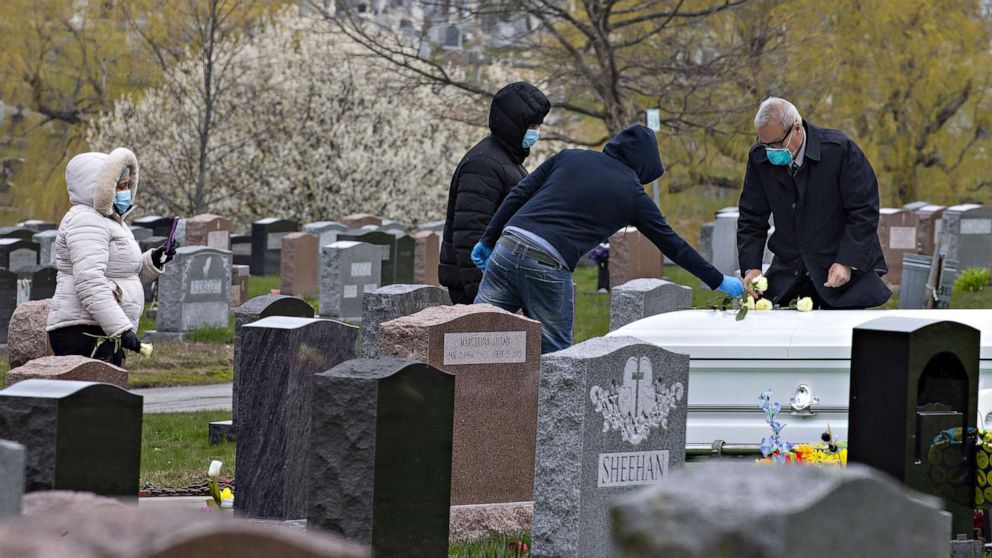 PHOTO: Mourners follow social distancing recommendations and wear face masks and gloves while attending a burial in Lawrence, Mass., April 24, 2020.