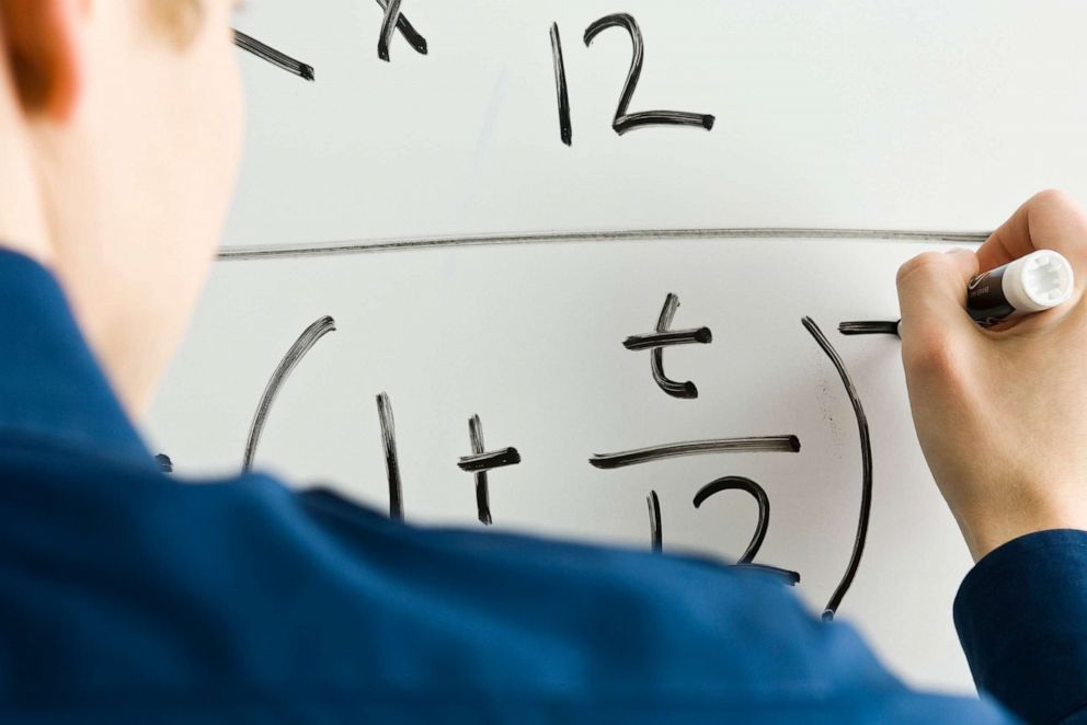 PHOTO: Student doing math on a whiteboard at school.