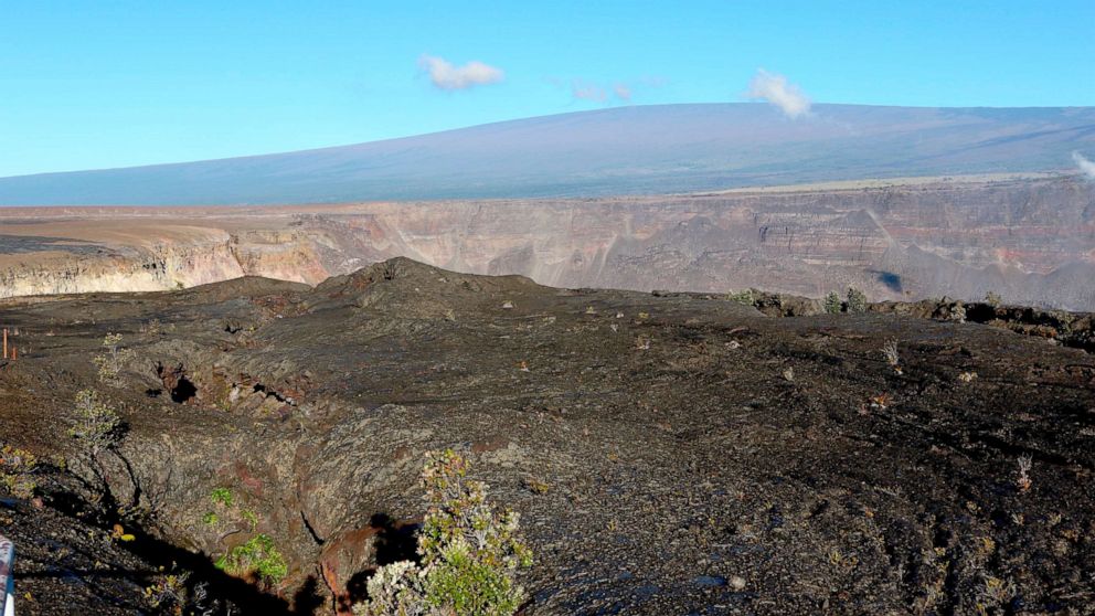 PHOTO: Hawaii's Mauna Loa volcano, background, towers over the summit crater of Kilauea volcano in Hawaii Volcanoes National Park on the Big Island on April 25, 2019.
