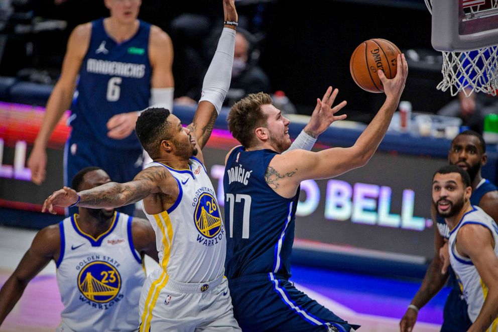 PHOTO: Dallas Mavericks guard Luka Doncic (77) drives to the basket past Golden State Warriors forward Kent Bazemore (26) and forward Draymond Green (23) during the first quarter of the game at the American Airlines Center in Dallas, Feb 6, 2021.