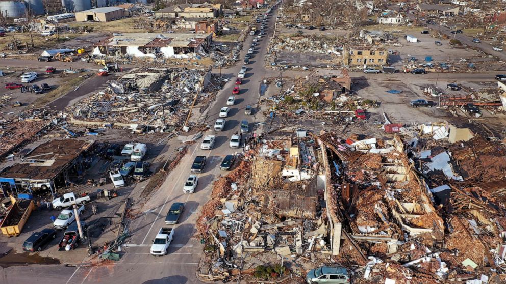 PHOTO: Cars drive though the remains of homes and businesses destroyed after a tornado ripped through town the previous evening, Dec. 11, 2021 in Mayfield, Ky.