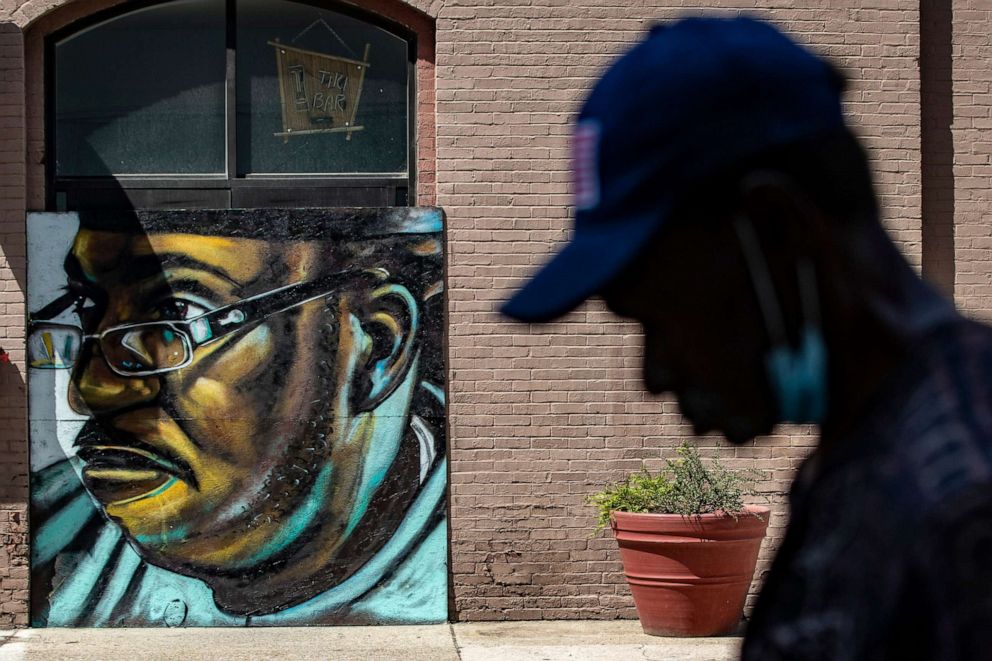 PHOTO: A pedestrian walks past a mural of David McAtee, June 3, 2020, painted by artist Damon Thompson on plywood outside the Limbo Tiki Bar in downtown Louisville, Ky. McAtee was shot and killed during a confrontation with police June 1, 2020.