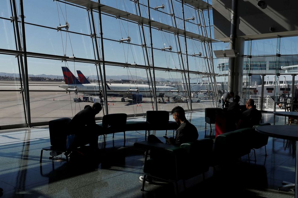 PHOTO: Travelers sit in a lounge area as Delta Air Lines planes park at a gate in McCarran International Airport in Las Vegas, Nevada, U.S., on Feb. 14, 2020.