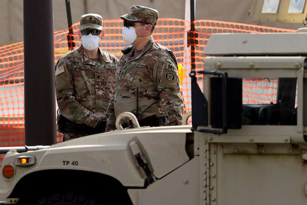 PHOTO: Soldiers from the Maryland National Guard stand guard at a site they build for screening people for the coronavirus in a parking lot at FedEx Field, March 30, 2020 in Landover, Md.