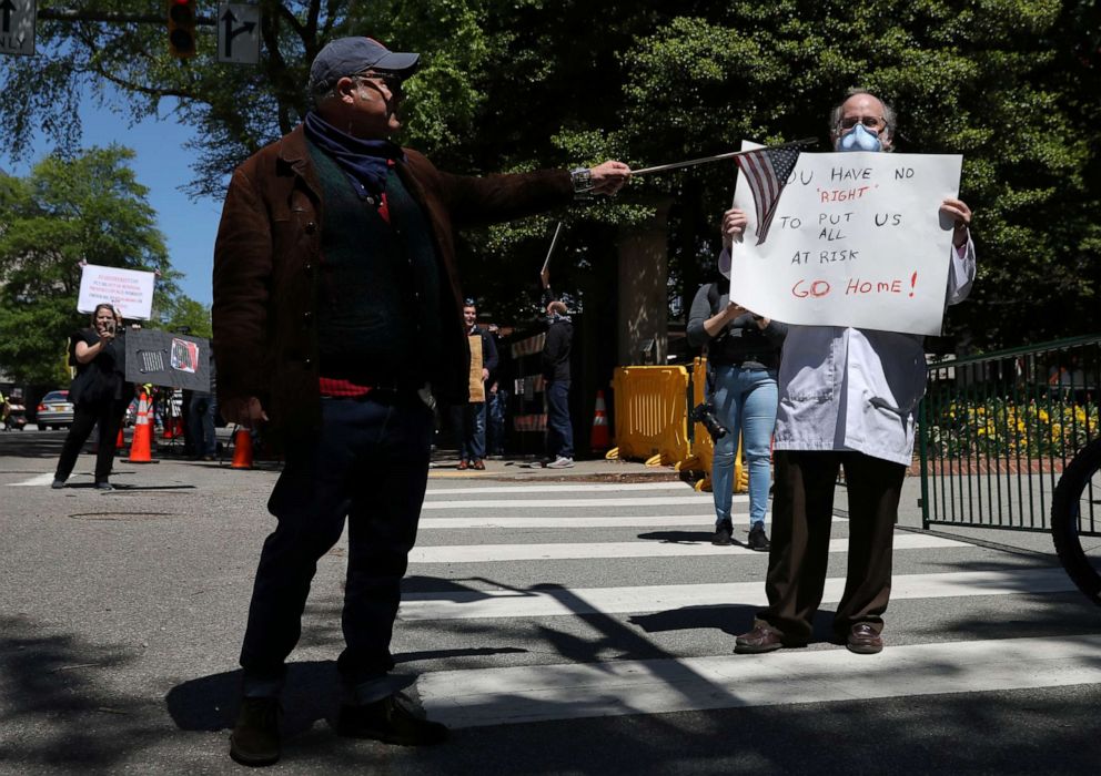 PHOTO: A demonstrator gestures with a flag on a stick at counter-protester Dr. Erich Bruhn during a protest against measures put into place to limit the spread of coronavirus and call for the reopening of the state in Richmond, Va., April 22, 2020.