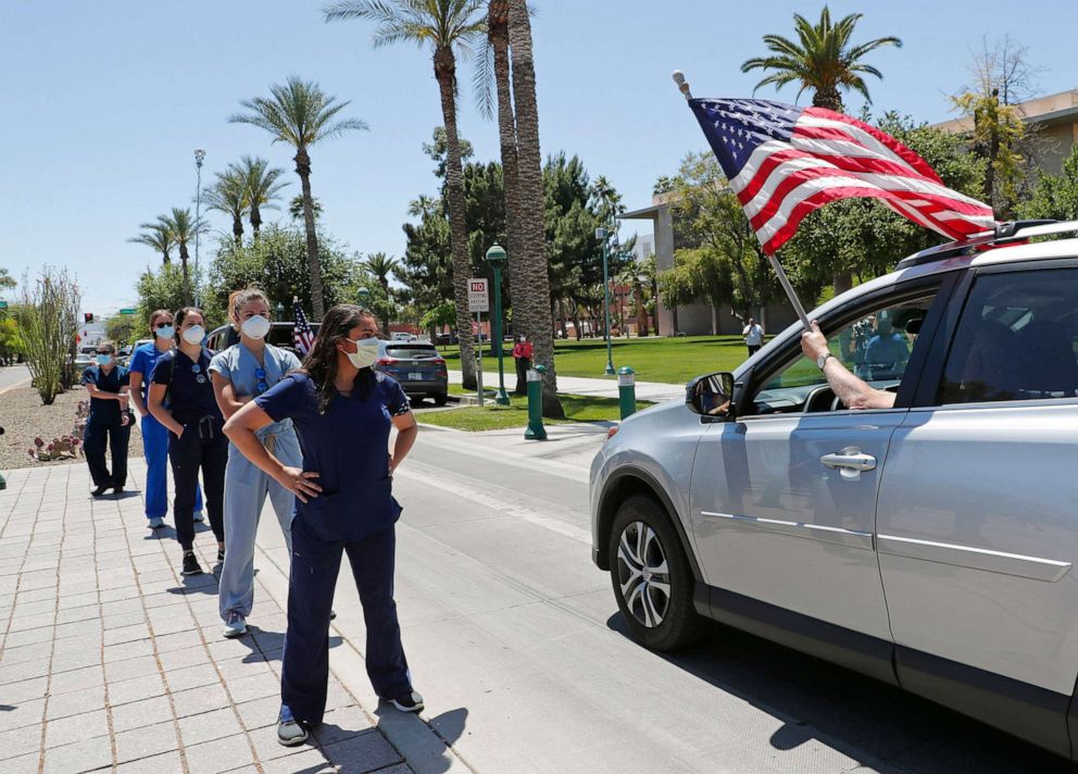PHOTO: Healthcare workers stand in counter-protest to drivers passing in front of the Arizona State Capitol in protest of Gov. Doug Ducey's stay-at-home order to combat the coronavirus, April 20, 2020.
