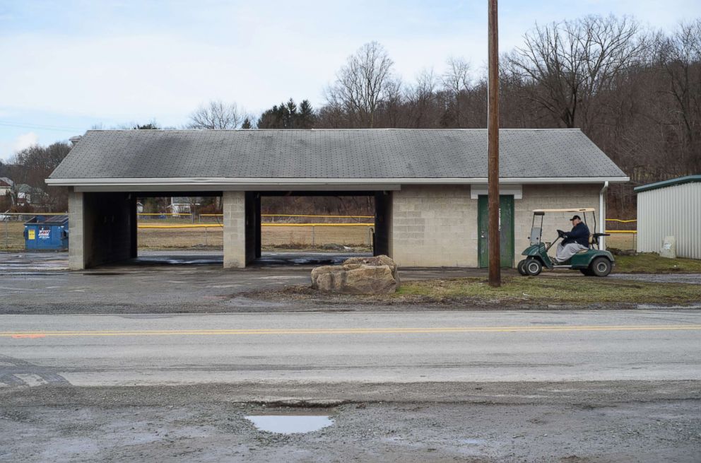 PHOTO: A man rides a golf cart past Ed's Car Wash where several people were found dead and one injured after a shooting, Jan. 28, 2018 in Melcroft, Pa.