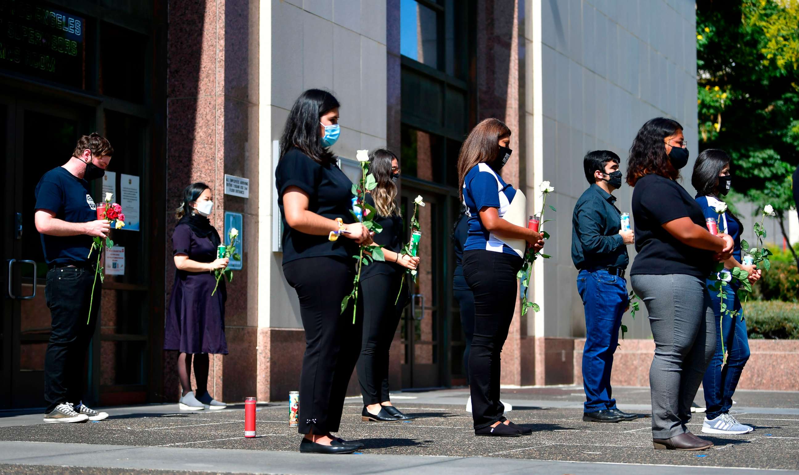 PHOTO: People hold roses while attending a memorial, honoring more than 5,700 residents of Los Angeles who lost their lives to coronavirus, in Los Angeles, California, on August 31, 2020.