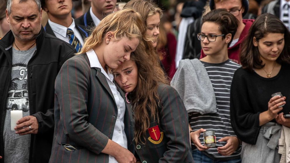 PHOTO: Schoolgirls comfort each other as they view flowers and tributes near Al Noor mosque, March 18, 2019 in Christchurch, New Zealand.