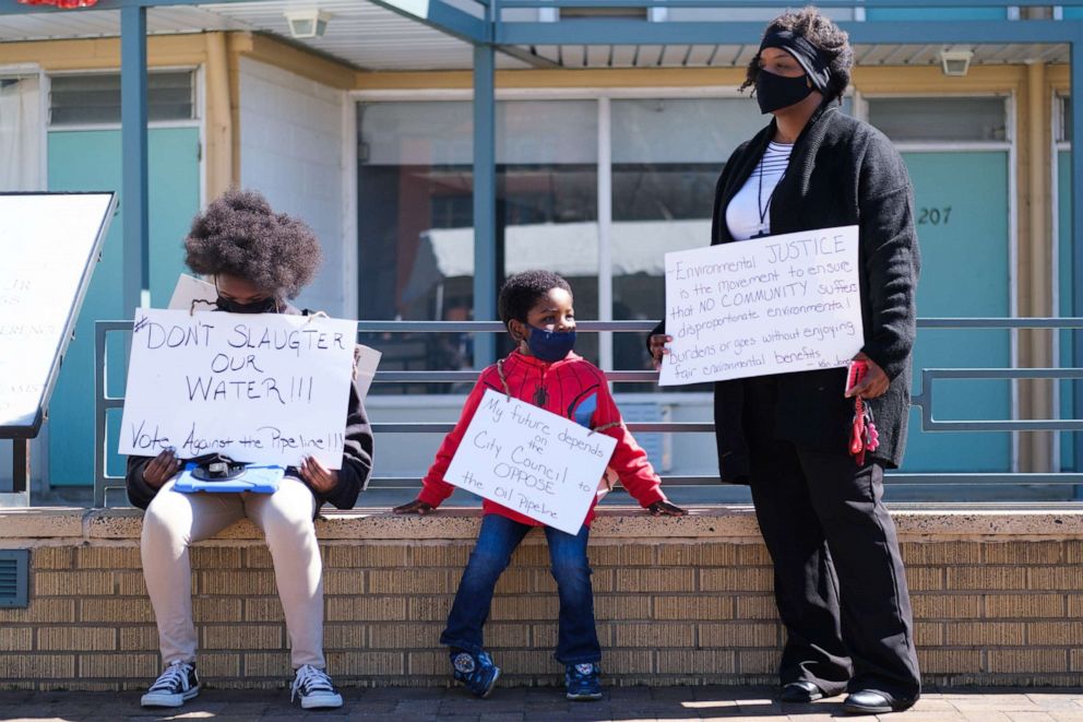 PHOTO: Kizzy Jones, a co-founder of Memphis Community Against the Pipeline, holds signs outside the National Civil Rights Museum with her family during a rally against the construction of the Byhalia Connection Pipeline, Feb. 23, 2021, in Memphis, Tenn.