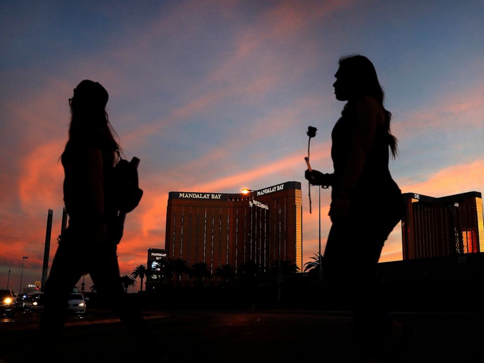 PHOTO: In this April 1, 2018, file photo, people carry flowers as they walk near the Mandalay Bay hotel and casino during a vigil for victims and survivors of a mass shooting in Las Vegas.