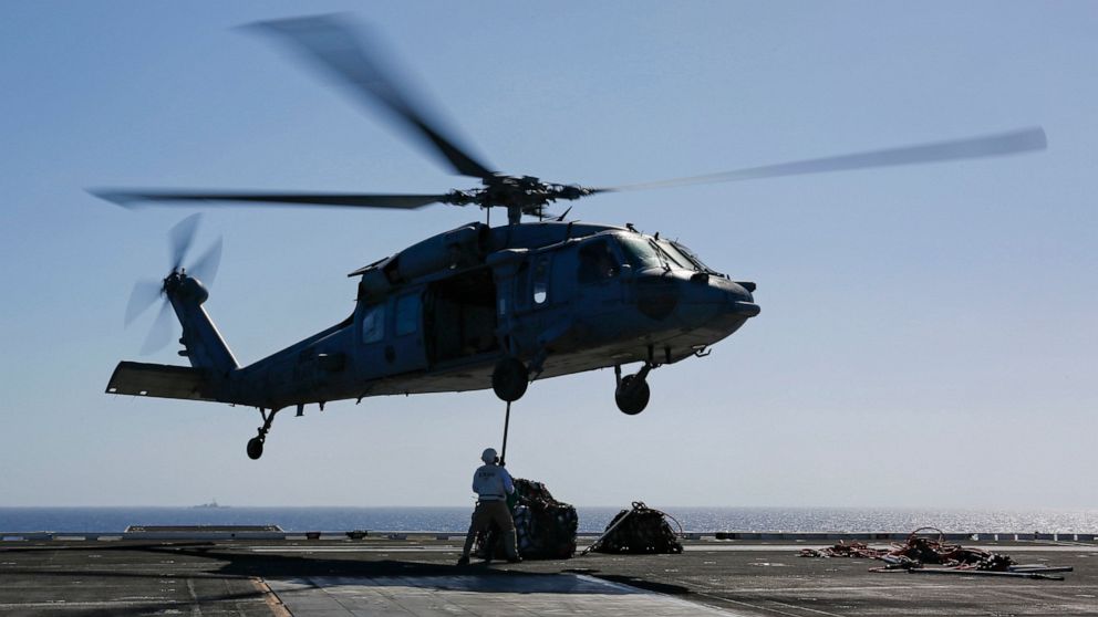 PHOTO: In this Friday, May 10, 2019, photo released by the U.S. Navy, logistics specialists attach cargo to an MH-60S Sea Hawk helicopter on the flight deck of the Nimitz-class aircraft carrier USS Abraham Lincoln in the Persian Gulf.