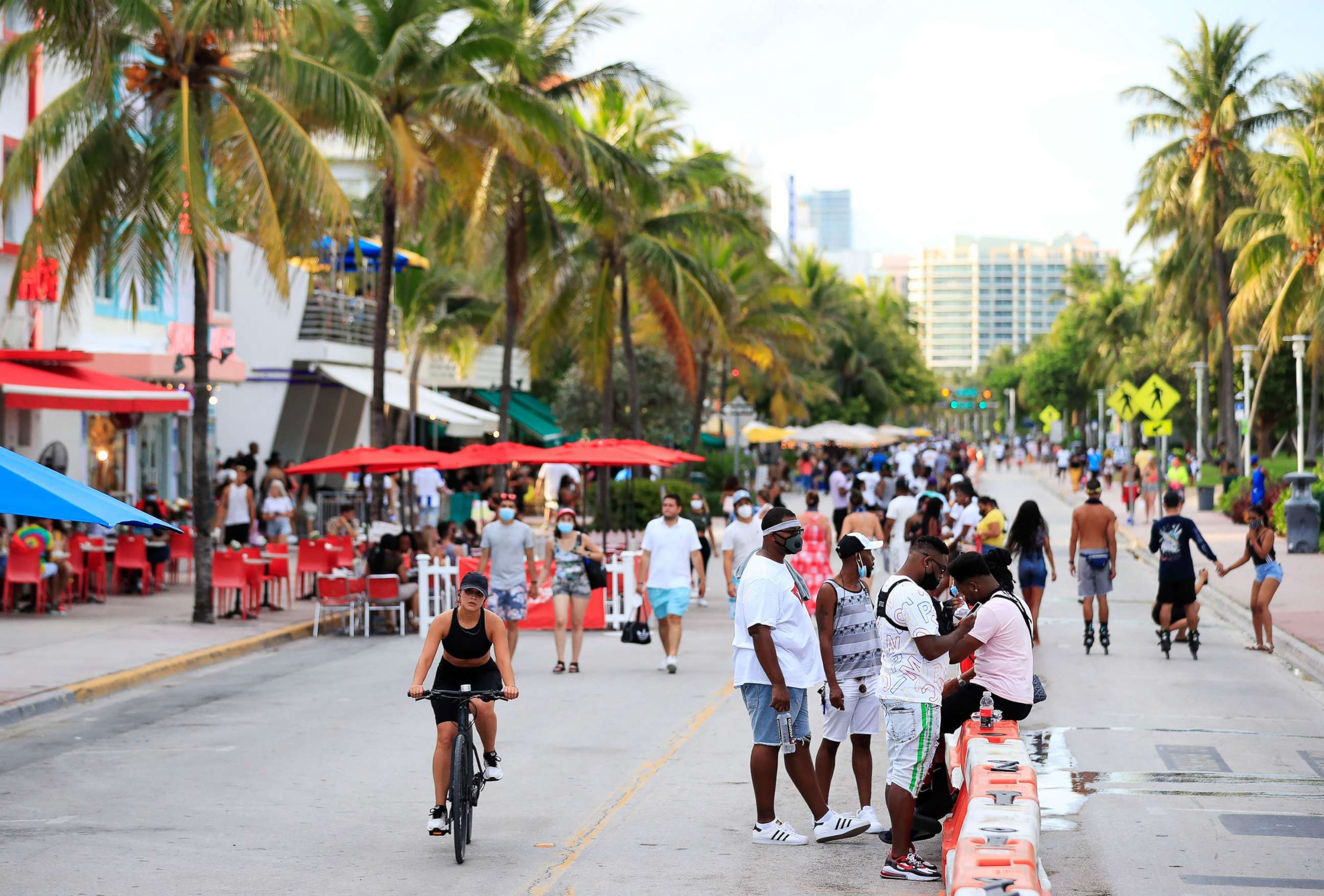 PHOTO: A woman rides her bike past pedestrians on Ocean Drive on July 3, 2020, in the South Beach neighborhood of Miami Beach, Fla.