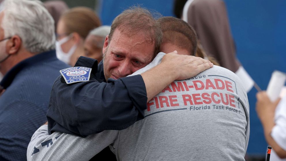 PHOTO: Rescue workers with the Miami-Dade Fire Rescue embrace after a moment of silence was held for the victims of the collapsed Champlain Towers South condominium in Surfside, Florida, on July 7, 2021.