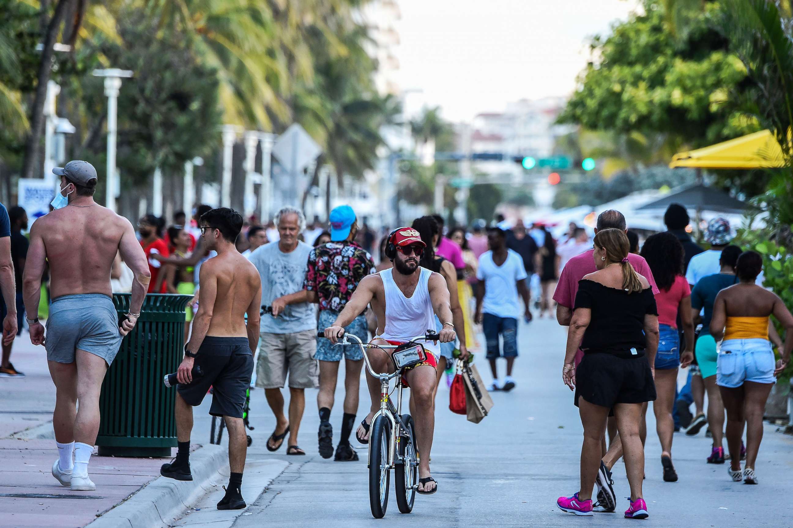 PHOTO: A man rides a bicycle as people walk on Ocean Drive in Miami Beach on June 26, 2020.