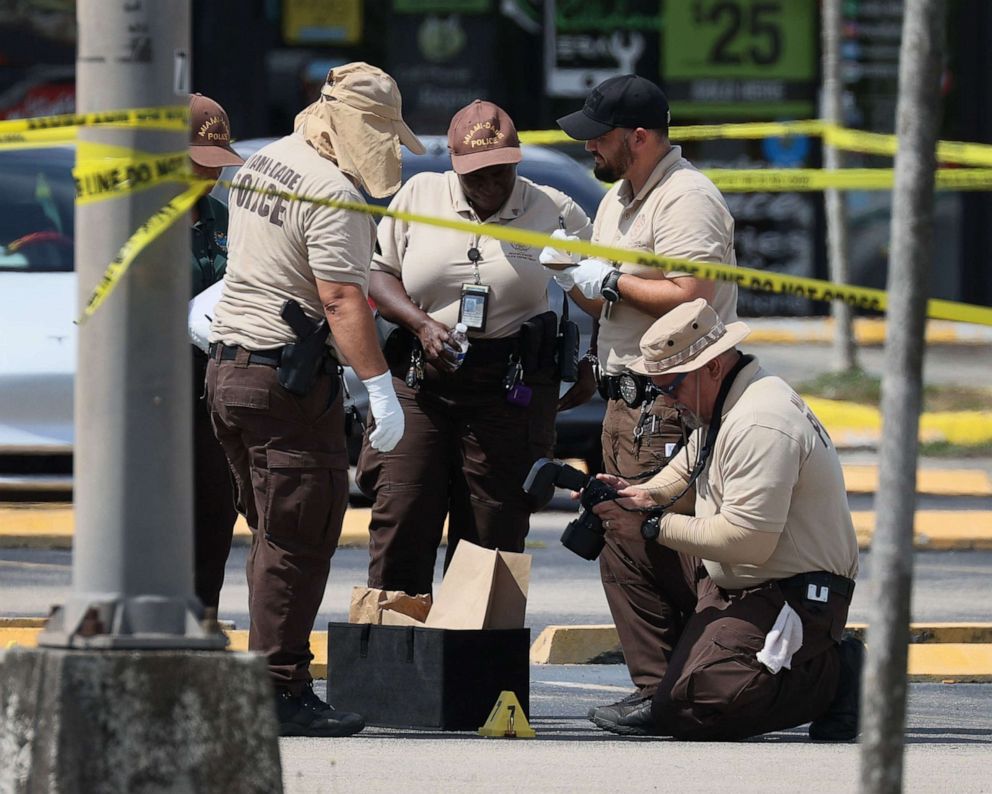 PHOTO: Miami-Dade police officers collect evidence near shell case evidence markers where a mass shooting took place outside of a banquet hall on May 30, 2021, in Hialeah, Fla.
