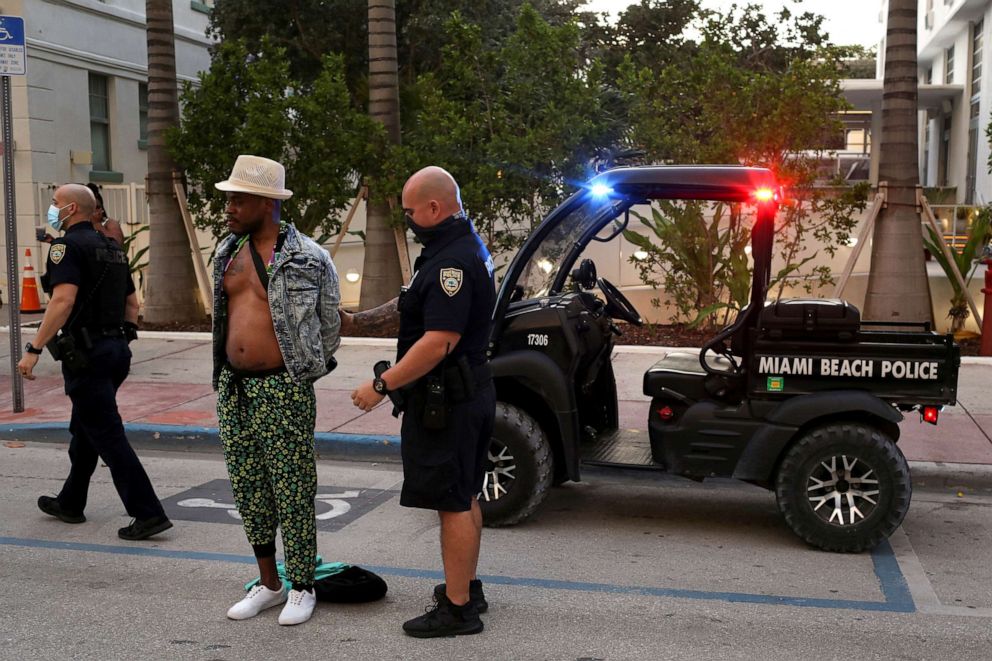 PHOTO: A man is detained by Miami Beach police officers for not paying the bill at a restaurant, ahead of an 8pm curfew imposed by local authorities in Miami Beach, Florida, March 27, 2021.