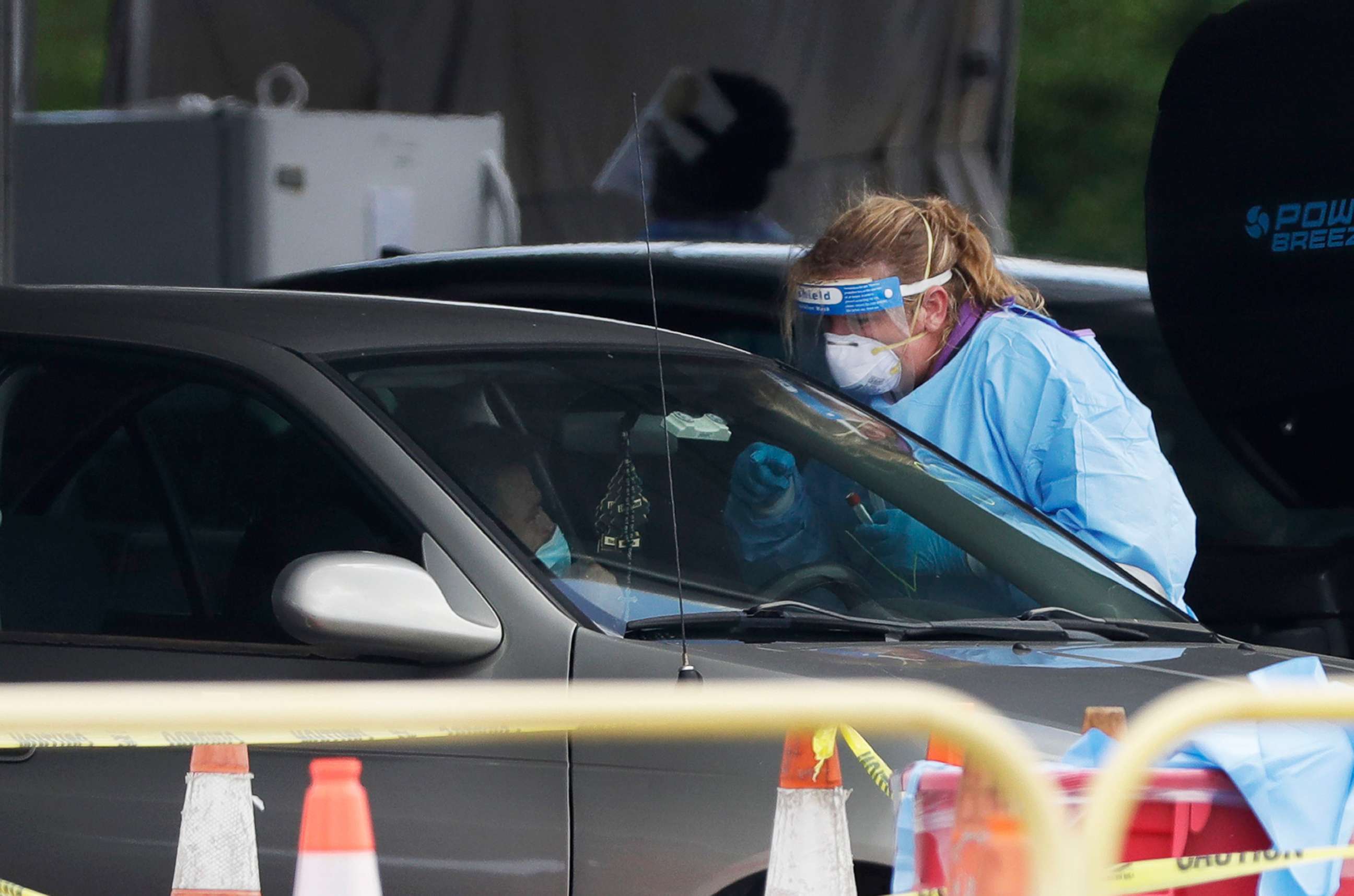 PHOTO: A health care worker prepares to test a driver in line at a drive-thru COVID-19 testing site outside Hard Rock Stadium, July 8, 2020, in Miami Gardens, Fla.