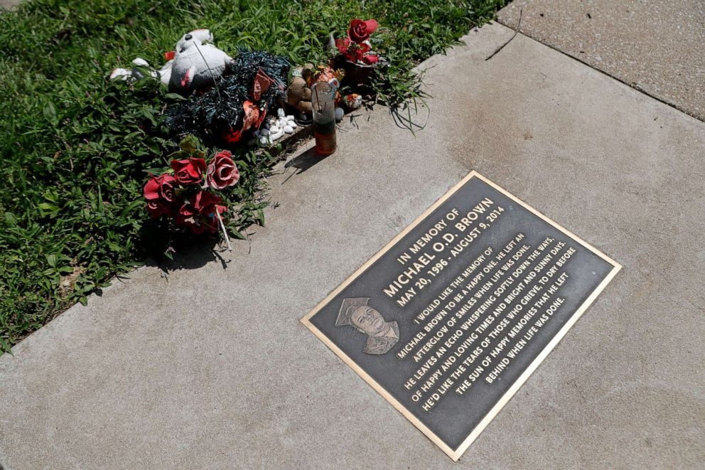 PHOTO: In this July 25, 2019, photo, flowers and other items lay near a memorial plaque in the sidewalk near the spot where Michael Brown was shot and killed by a police officer five years ago in Ferguson, Mo.