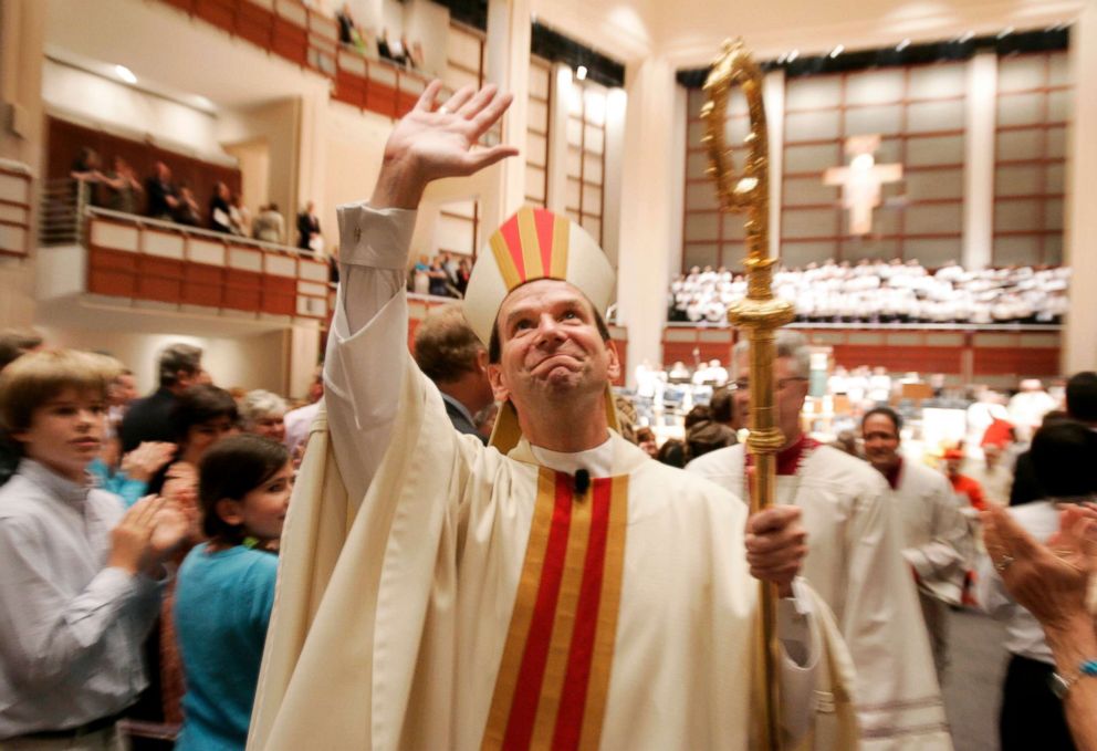 PHOTO: Bishop Michael Burbidge waves to the assembled crowd as he leaves Meymandi Concert Hall after being installed as the fifth Bishop of Raleigh, in Raleigh, N.C., Aug. 4, 2006.