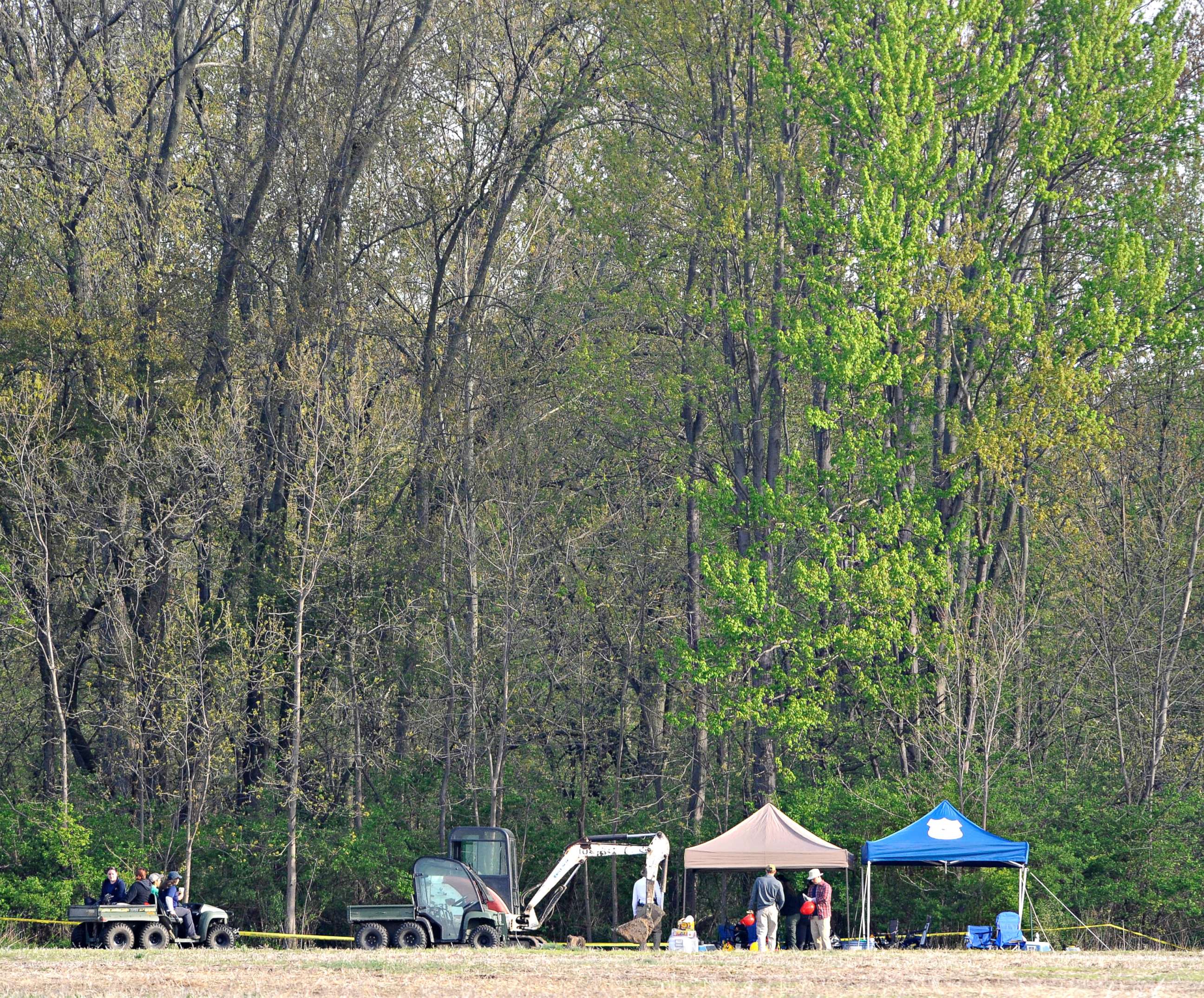 PHOTO: Investigators set up their equipment under tents before beginning their work at a dig site along a rural wooded area in Macomb Township, Mich., May 9, 2018.