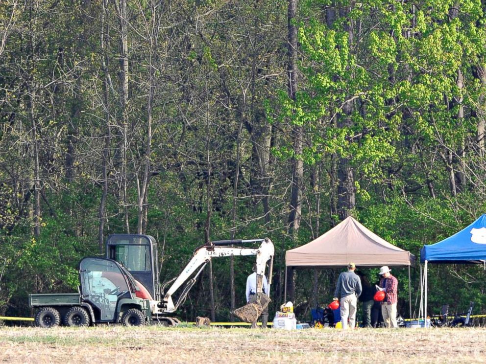 PHOTO: Investigators set up their equipment under tents before beginning their work at a dig site along a rural wooded area in Macomb Township, Mich., May 9, 2018.