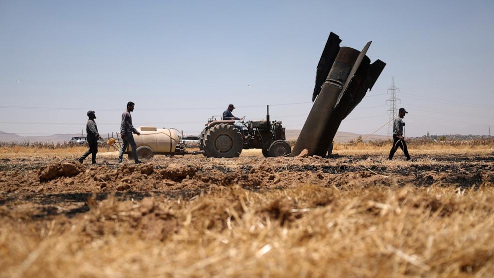 PHOTO: Farmers spray water in a burned agricultural field next to a projectile near the town of Najha, Syria, June 8, 2026, after debris from Iranian missile launches during the Iran-Israel conflict fell in the area.