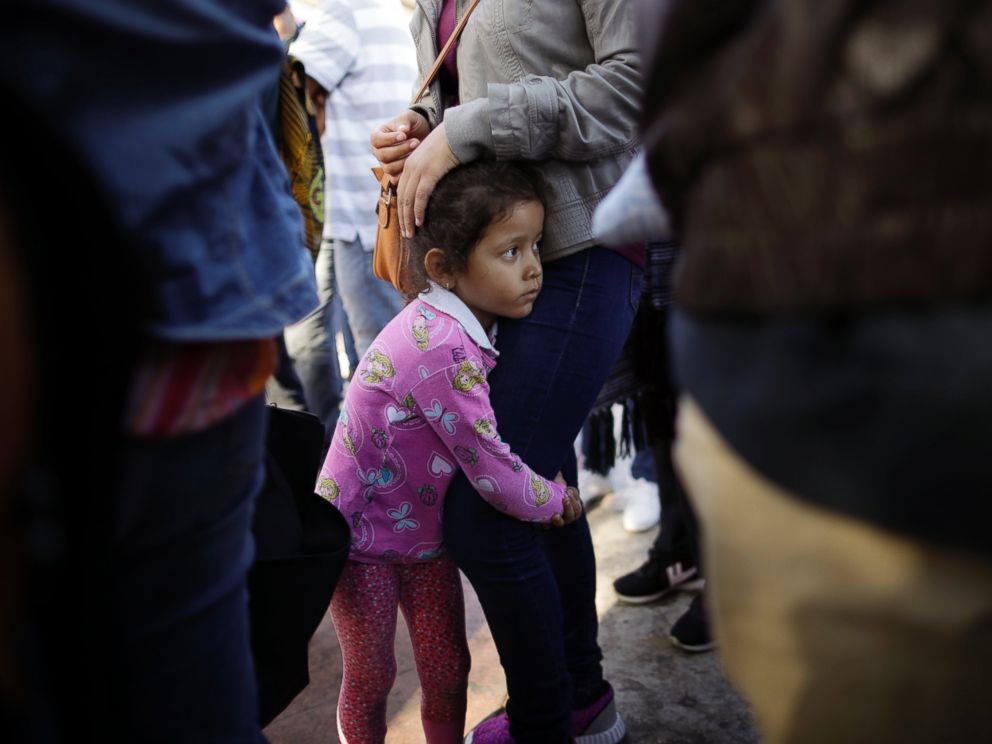 In this June 13, 2018 file photo, Nicole Hernandez, of the Mexican state of Guerrero, holds on to her mother as they wait with other families to request political asylum in the United States, across the border in Tijuana, Mexico.