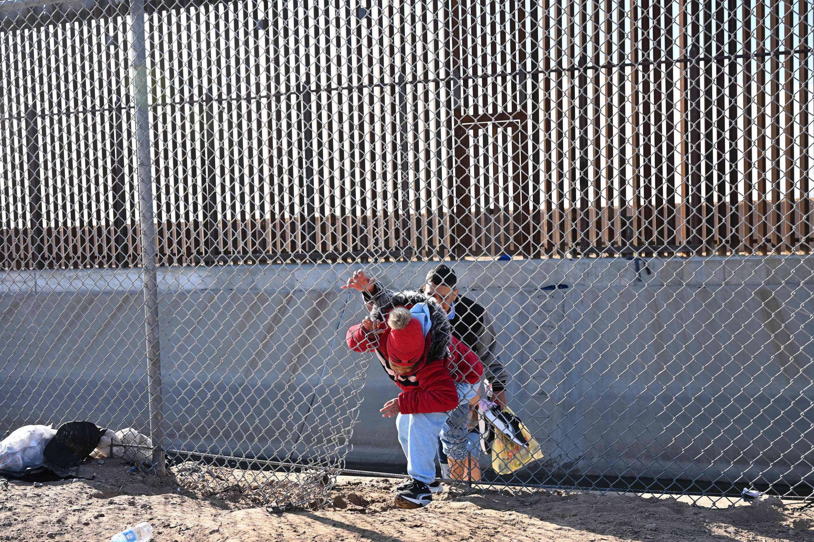 PHOTO: A family of migrants from Colombia climbs through a canal fence after crossing under a hole in the US-Mexico border wall, Dec. 19, 2022, in El Paso, Texas.